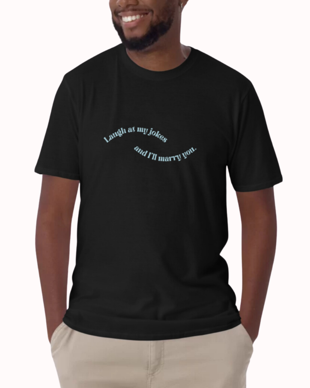 Front view of a black T-Shirt worn by a smiling man, featuring the phrase 'Laugh at my jokes and I will marry you' on the chest. Perfect for fans of funny merchandise, bold humor, and witty sarcasm. 