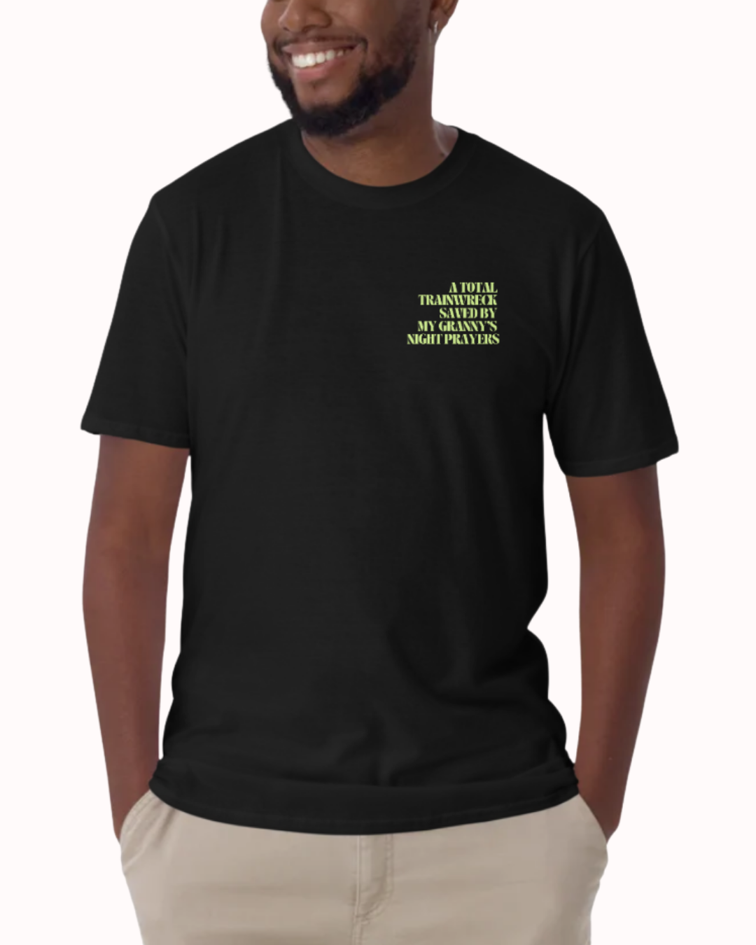 Front view of a Black t-shirt worn by a smiling man, featuring the phrase "A total trainwreck saved my granny's night prayers" on the chest and back. Perfect for fans of funny merchandise, bold humor, and witty sarcasm.