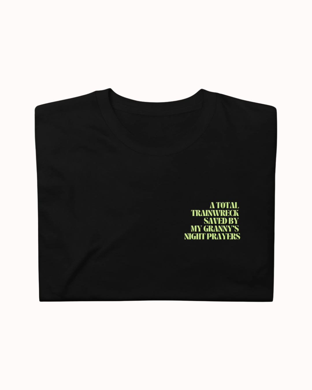 Folded Black t-shirt featuring the ironic phrase "A total trainwreck saved my granny's night prayers". Perfect for fans of funny merchandise, bold humor, and witty sarcasm.