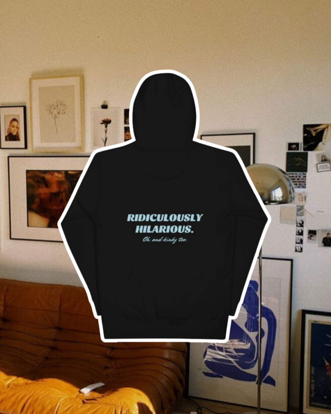 Black hoodie with the phrase 'Ridiculously hilarious. Oh, and kinky too' on the back, displayed against a vibrant living room with cozy elements and colorful frames. A playful and bold design for fans of funny merchandise and sarcasm.