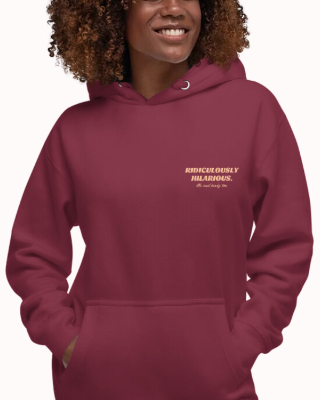 Front view of a maroon hoodie worn by a smiling woman, featuring the phrase 'Ridiculously hilarious. Oh, and kinky too' on the chest and back. Perfect for fans of funny merchandise, bold humor, and witty sarcasm.