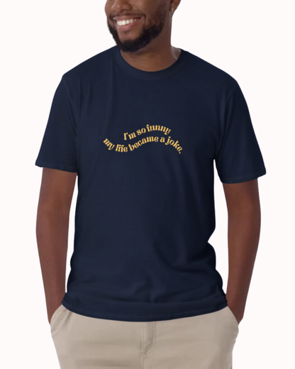 Front view of a navy T-Shirt worn by a smiling man, featuring the phrase 'I'm so funny my life became a joke' on the chest. Perfect for fans of funny merchandise, bold humor, and witty sarcasm. 