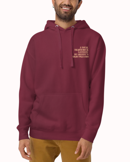 
Front view of a Maroon hoodie worn by a smiling man, featuring the phrase "A total trainwreck saved my granny's night prayers" on the chest and back. Perfect for fans of funny merchandise, bold humor, and witty sarcasm.
