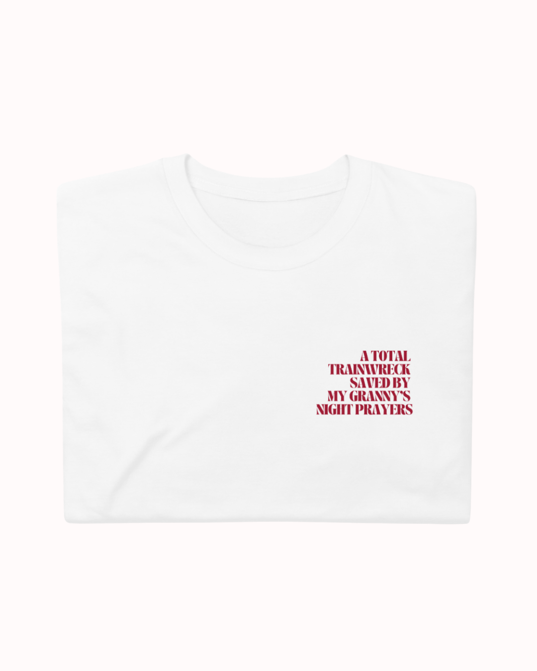 Folded White t-shirt featuring the ironic phrase "A total trainwreck saved my granny's night prayers". Perfect for fans of funny merchandise, bold humor, and witty sarcasm.