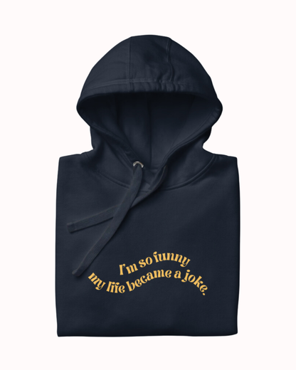 Folded navy blazer hoodie featuring the ironic phrase 'I'm so funny my life became a joke'. Perfect for fans of funny merchandise, bold humor, and witty sarcasm.