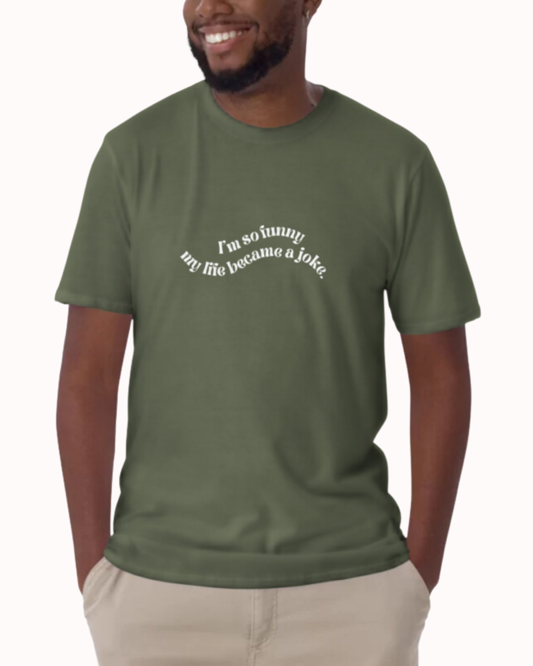 Front view of a military green T-Shirt worn by a smiling man, featuring the phrase 'I'm so funny my life became a joke' on the chest. Perfect for fans of funny merchandise, bold humor, and witty sarcasm. 