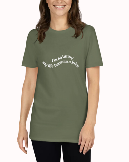 Front view of a military green T-Shirt worn by a smiling woman, featuring the phrase 'I'm so funny my life became a joke' on the chest. Perfect for fans of funny merchandise, bold humor, and witty sarcasm.