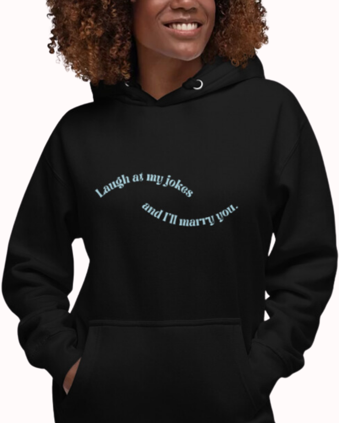 Front view of a black hoodie worn by a smiling woman, featuring the phrase 'Laugh at my jokes and I'll marry you' on the chest. Perfect for fans of funny merchandise, bold humor, and witty sarcasm.