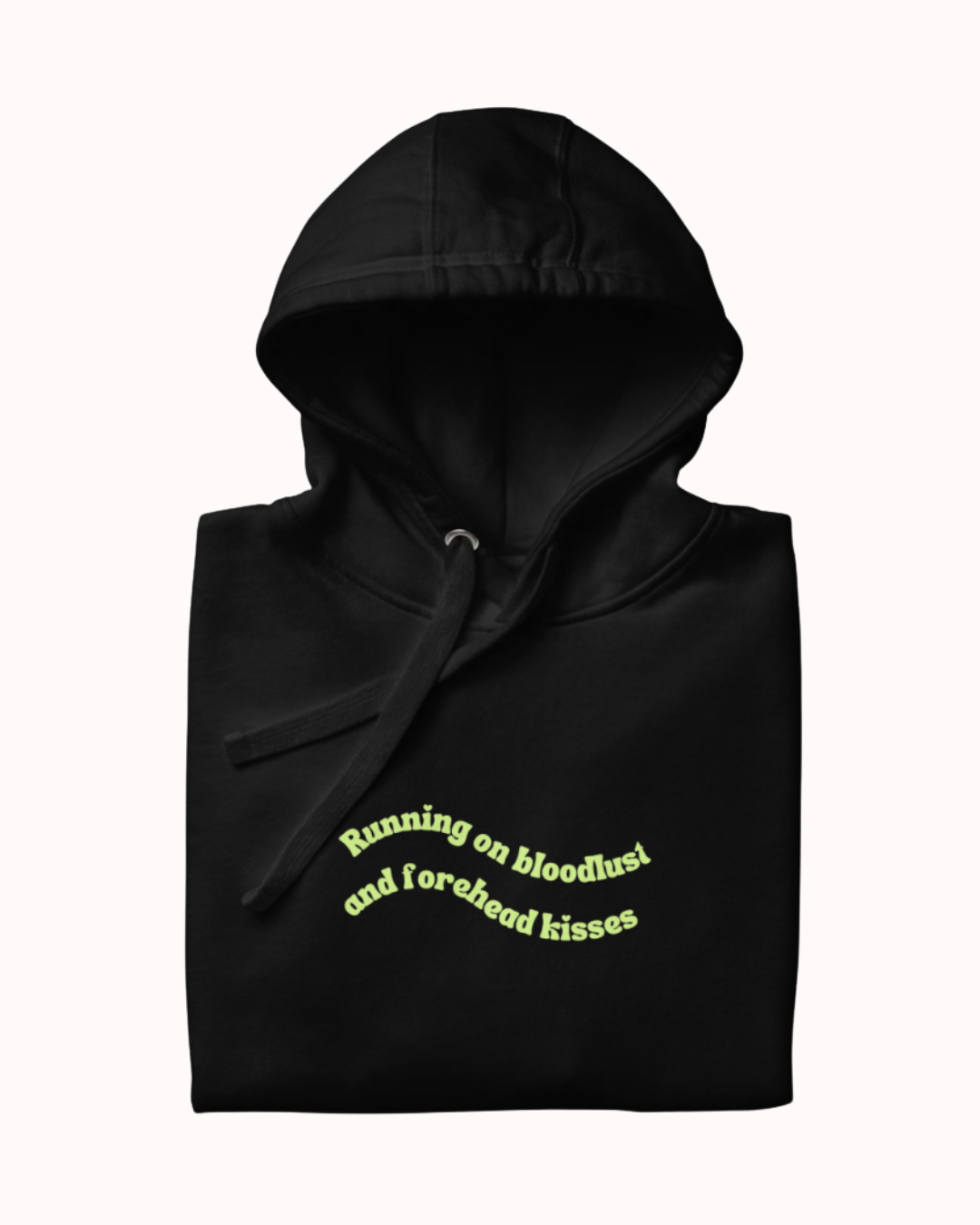 Folded Black hoodie featuring the ironic phrase "Running on bloodlust and forehead kisses". Perfect for fans of funny merchandise, bold humor, and witty sarcasm.
