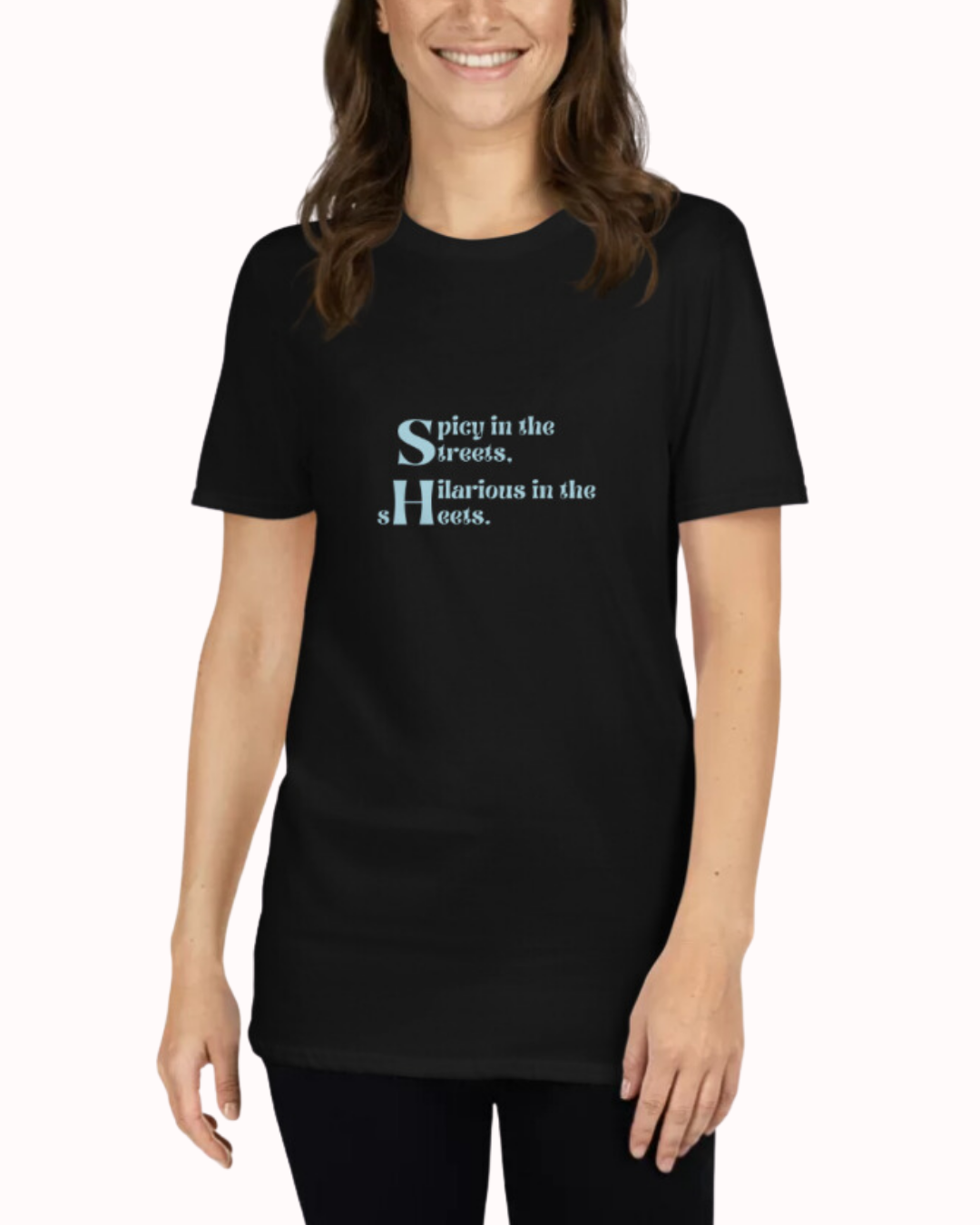 Front view of a black T-Shirt worn by a smiling woman, featuring the phrase 'Spicy in the streets, Hilarious in the sheets' on the chest. Perfect for fans of funny merchandise, bold humor, and witty sarcasm.