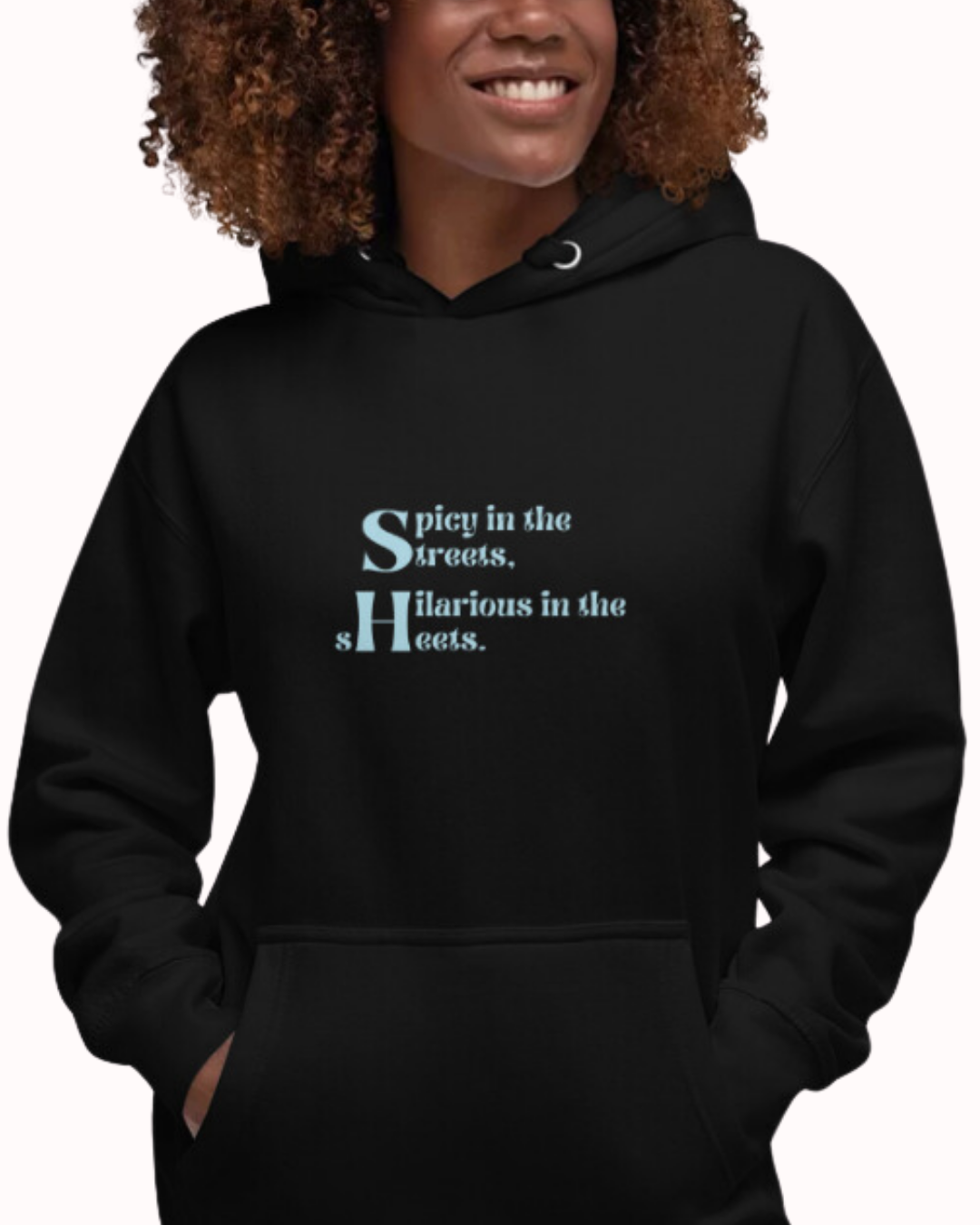 Front view of a black hoodie worn by a smiling woman, featuring the phrase 'Spicy in the streets, Hilarious in the sheets' on the chest. Perfect for fans of funny merchandise, bold humor, and witty sarcasm.