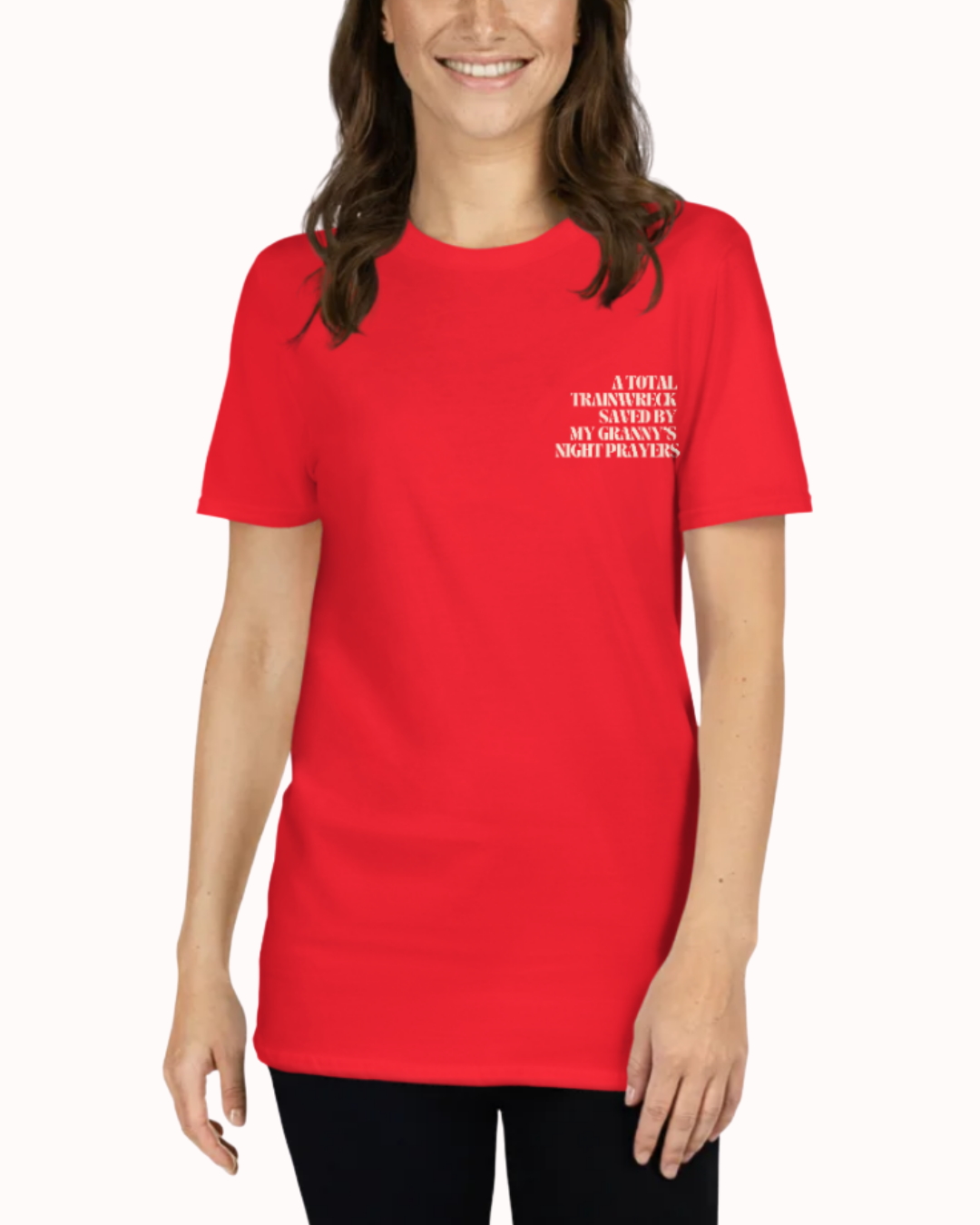 Front view of a Red t-shirt worn by a smiling woman, featuring the phrase "A total trainwreck saved my granny's night prayers" on the chest and back. Perfect for fans of funny merchandise, bold humor, and witty sarcasm.