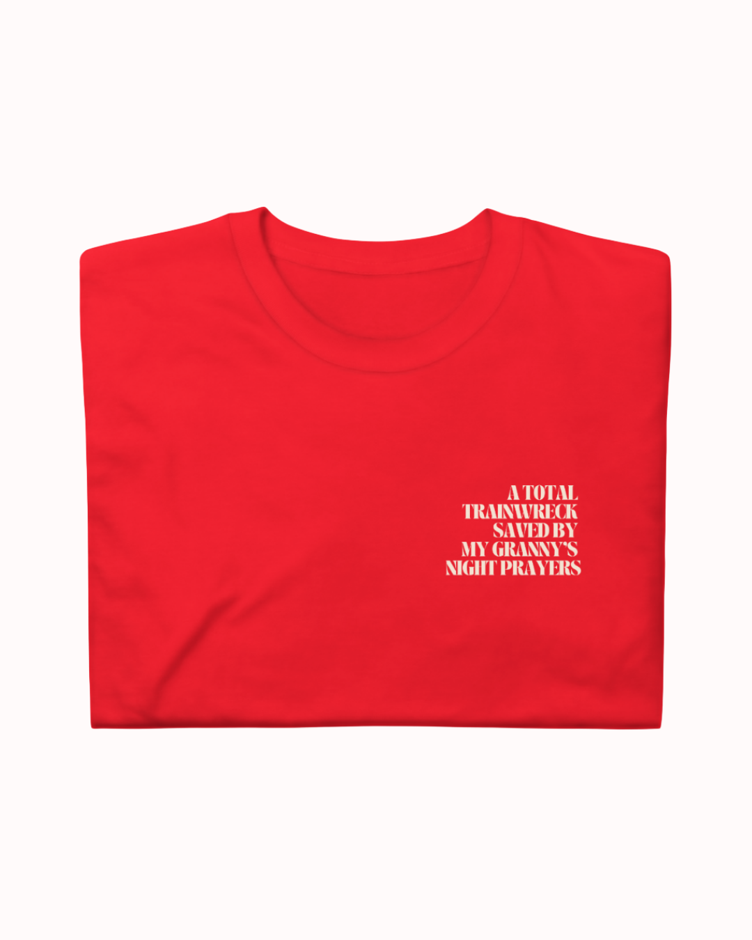 Folded Red t-shirt featuring the ironic phrase "A total trainwreck saved my granny's night prayers". Perfect for fans of funny merchandise, bold humor, and witty sarcasm.