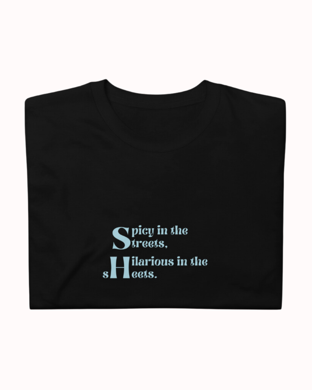 Folded black T-Shirt featuring the ironic phrase 'Spicy in the streets, Hilarious in the sheets'. Perfect for fans of funny merchandise, bold humor, and witty sarcasm. 