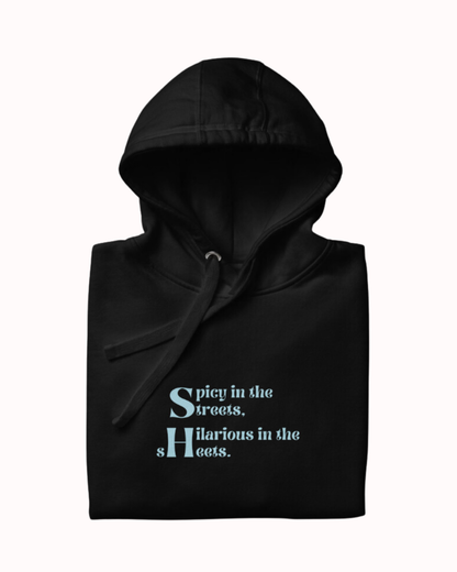 Folded black hoodie featuring the ironic phrase 'Spicy in the streets, Hilarious in the sheets'. Perfect for fans of funny merchandise, bold humor, and witty sarcasm.