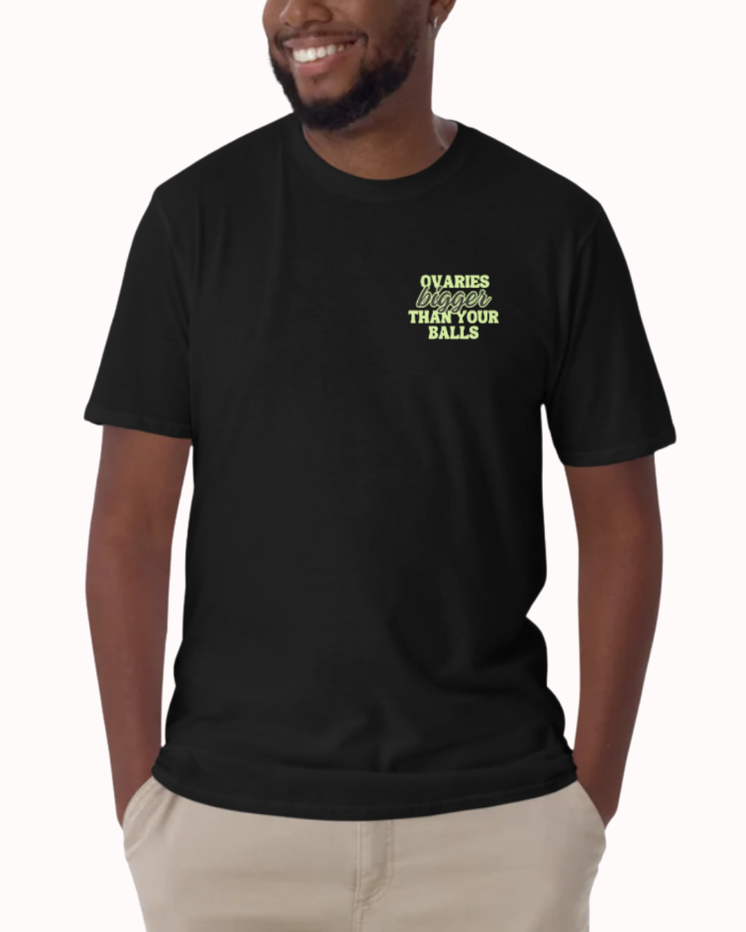 Front view of a Black t-shirt worn by a smiling man, featuring the phrase "Ovaries bigger than your balls" on the chest and back. Perfect for fans of funny merchandise, bold humor, and witty sarcasm.