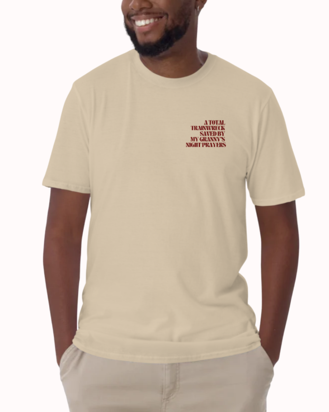Front view of a Sand t-shirt worn by a smiling man, featuring the phrase "A total trainwreck saved my granny's night prayers" on the chest and back. Perfect for fans of funny merchandise, bold humor, and witty sarcasm.