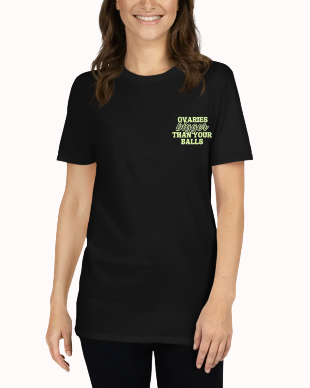 Front view of a Black t-shirt worn by a smiling woman, featuring the phrase "Ovaries bigger than your balls" on the chest and back. Perfect for fans of funny merchandise, bold humor, and witty sarcasm.