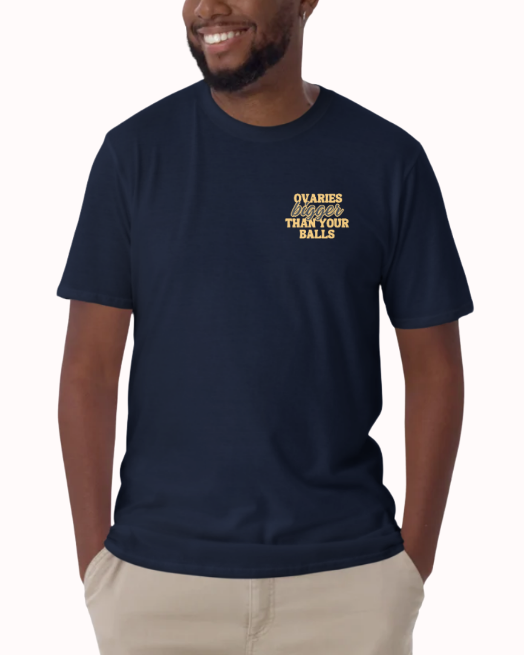 Front view of a Navy t-shirt worn by a smiling man, featuring the phrase "Ovaries bigger than your balls" on the chest and back. Perfect for fans of funny merchandise, bold humor, and witty sarcasm.