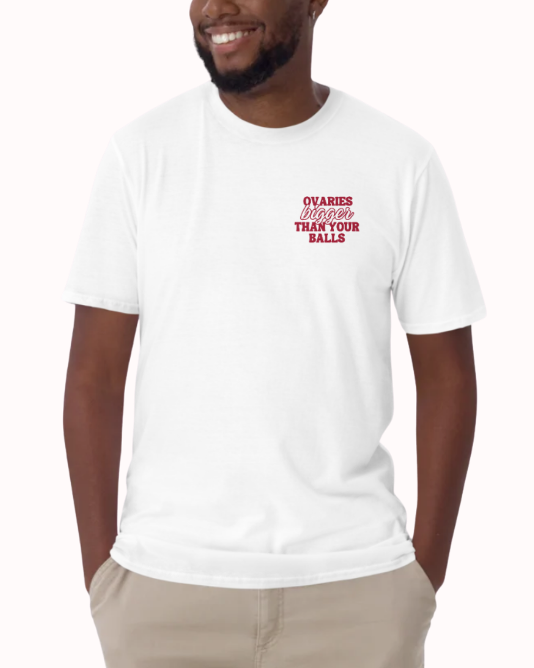 Front view of a White t-shirt worn by a smiling man, featuring the phrase "Ovaries bigger than your balls" on the chest and back. Perfect for fans of funny merchandise, bold humor, and witty sarcasm.