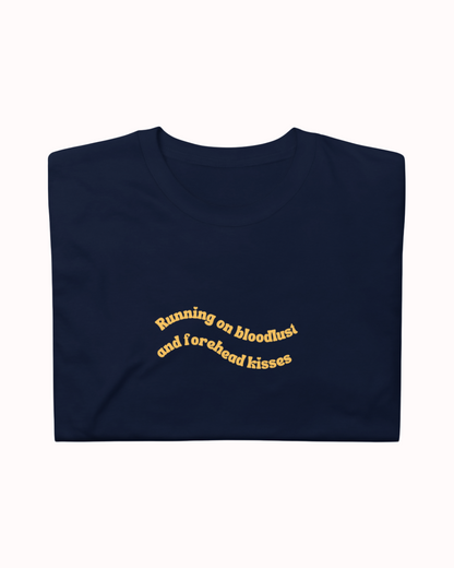 Folded Navy t-shirt featuring the ironic phrase "Running on bloodlust and forehead kisses". Perfect for fans of funny merchandise, bold humor, and witty sarcasm.