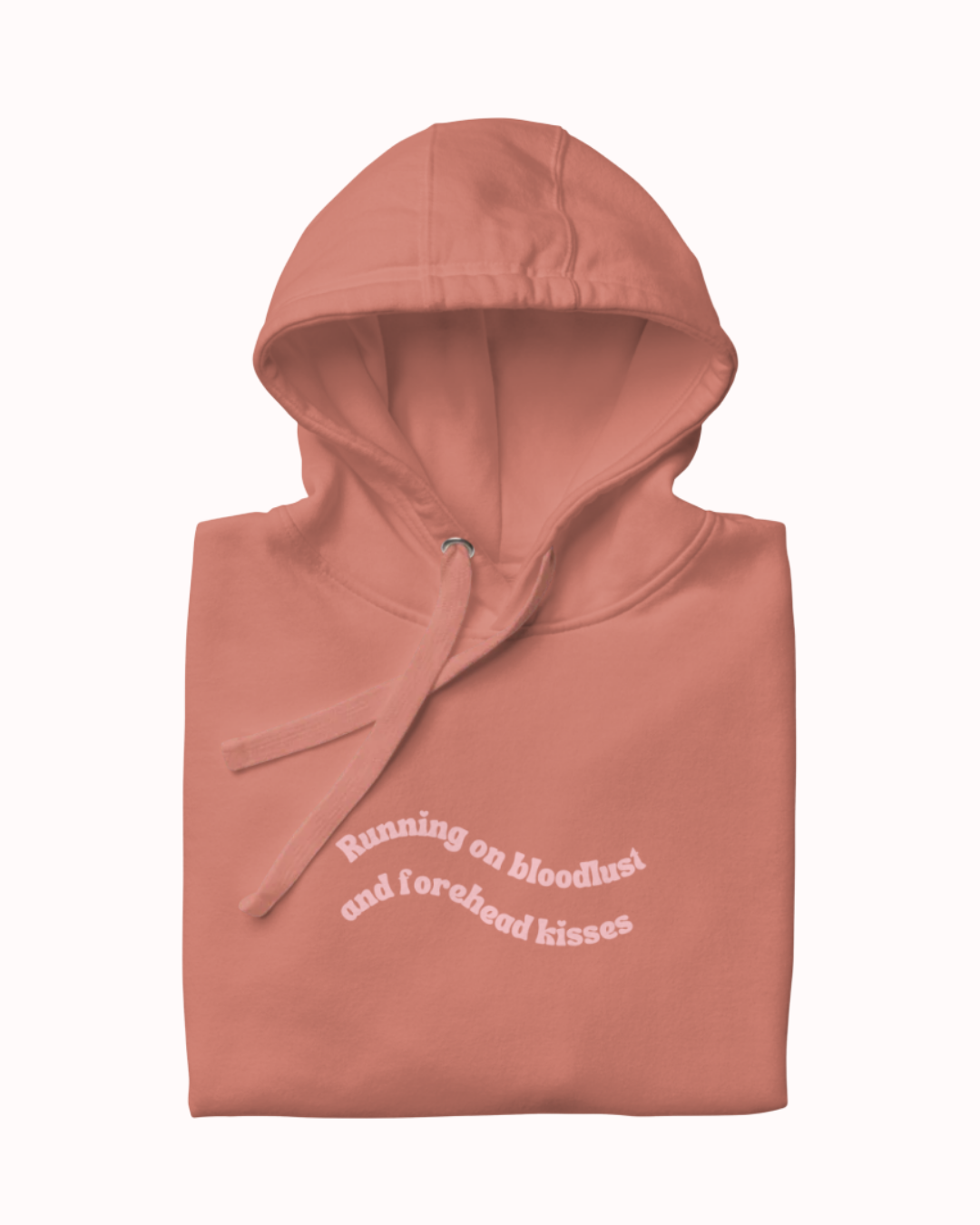 Folded Dusty Rose hoodie featuring the ironic phrase "Running on bloodlust and forehead kisses". Perfect for fans of funny merchandise, bold humor, and witty sarcasm.