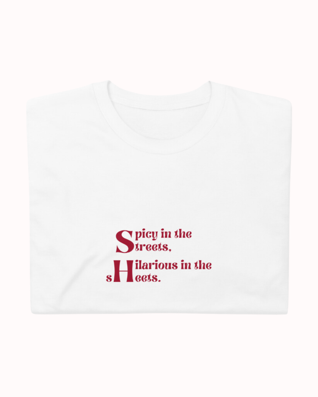 Folded white T-Shirt featuring the ironic phrase 'Spicy in the streets, Hilarious in the sheets'. Perfect for fans of funny merchandise, bold humor, and witty sarcasm. 