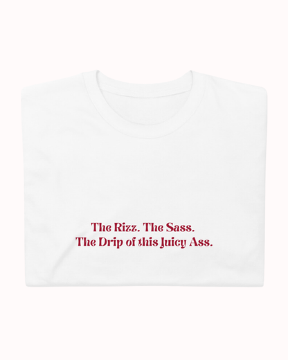 Folded white T-Shirt featuring the ironic phrase 'The rizz. The sass. The drip of this juicy ass'. Perfect for fans of funny merchandise, bold humor, and witty sarcasm. 